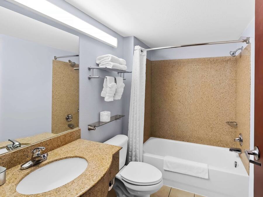 A bathroom with a granite sink, a toilet, a bathtub, and a shower curtain.