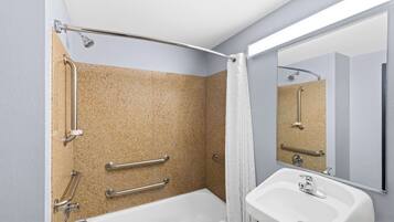 A bathroom with a bathtub, a sink, and a shower with grab bars.