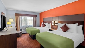 A hotel room with two beds, a desk, a TV, and a window with curtains.
