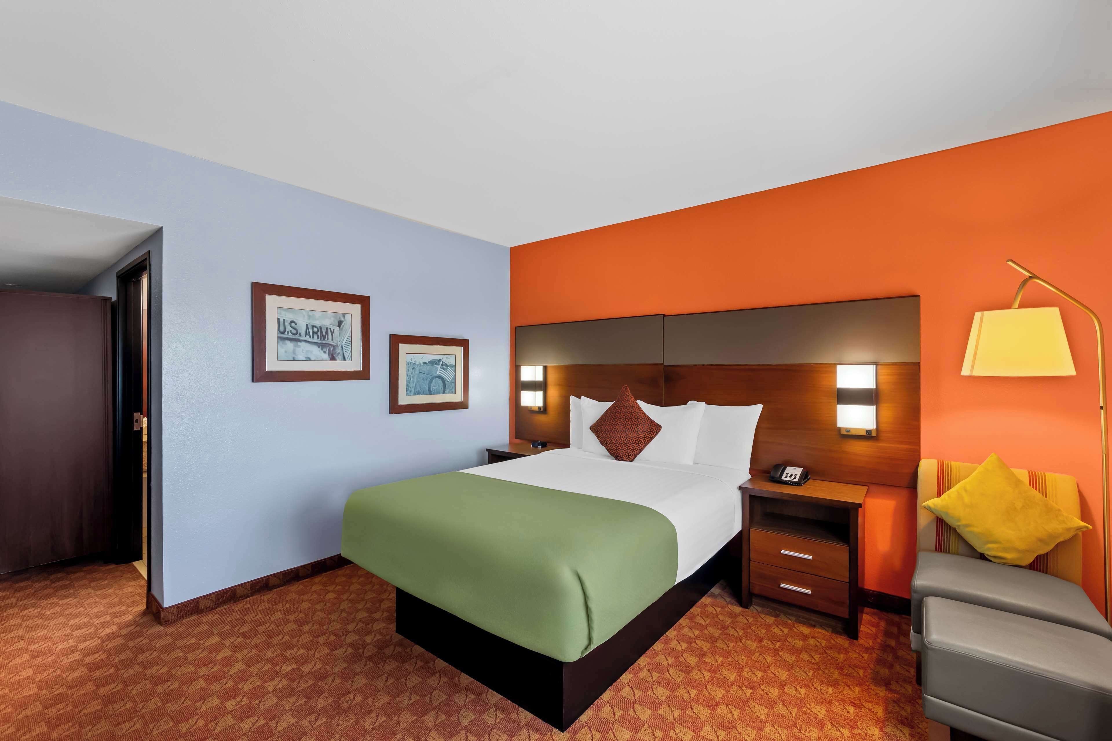 A hotel room with a bed, a nightstand, a desk, and a chair.