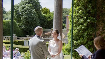 Une cérémonie de mariage en plein air, avec un sol en pierre et de la verdure.