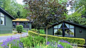A green building with a small porch and a well-maintained garden with various plants and flowers. - Broome Park Hotel (Canterbury)