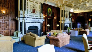 A grand room with a fireplace, ornate ceiling, and comfortable seating. - Broome Park Hotel (Canterbury)
