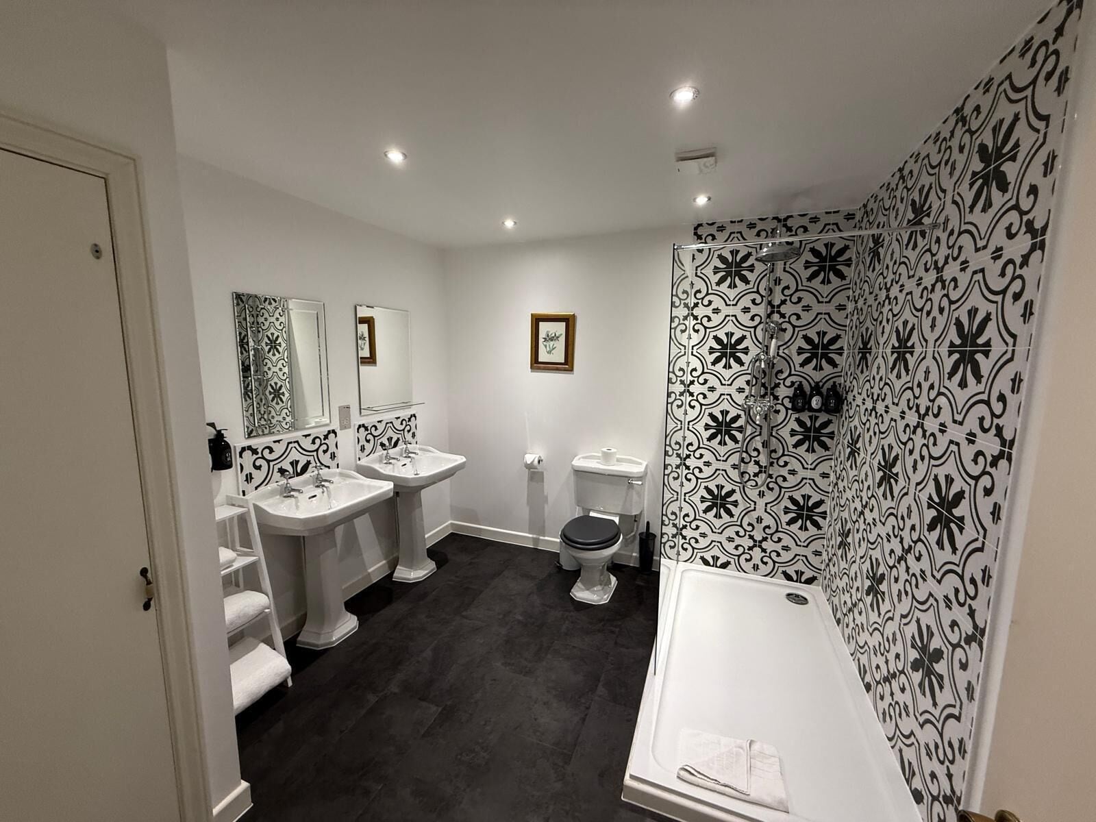 A bathroom with two sinks, a toilet, and a shower.