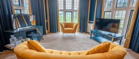 A living room with a yellow sofa, a television, and a chair.
