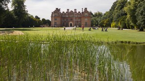 A large, historic building with a well-maintained lawn and a pond in the foreground. - Broome Park Hotel (Canterbury)