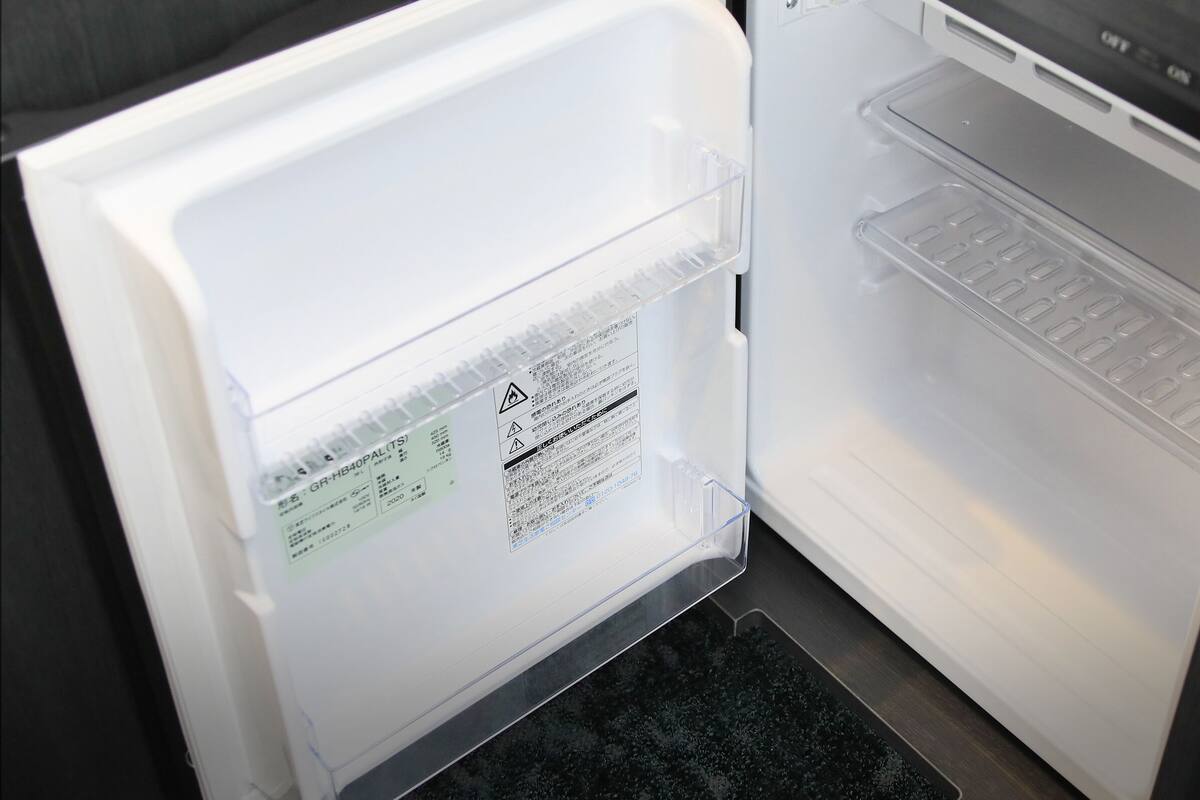 Un refrigerador abierto con un estante transparente y una etiqueta en la puerta.