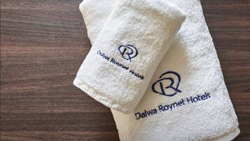 Two folded white towels with embroidered logos and text on a wooden surface.