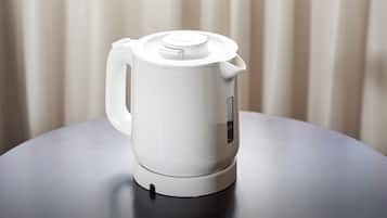 Una tetera eléctrica blanca sobre una mesa con un diseño moderno y sencillo.