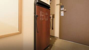 A corridor with a wooden door and a metal handle, a sign on the wall, and a door with a keycard reader.