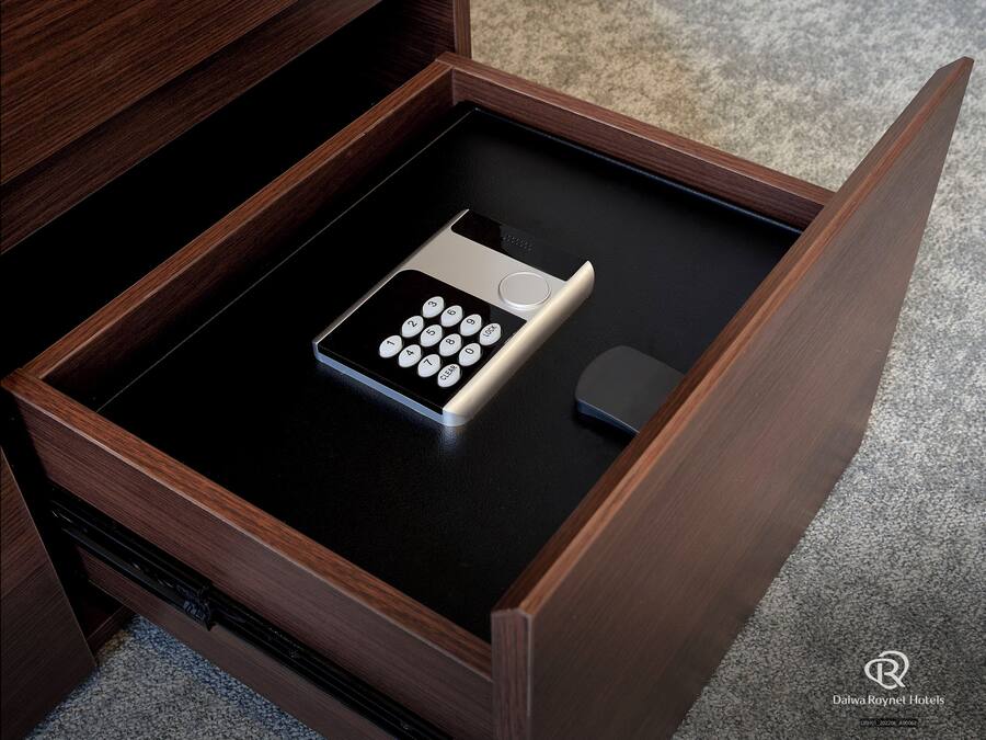 A drawer with a remote control and a small electronic device inside.