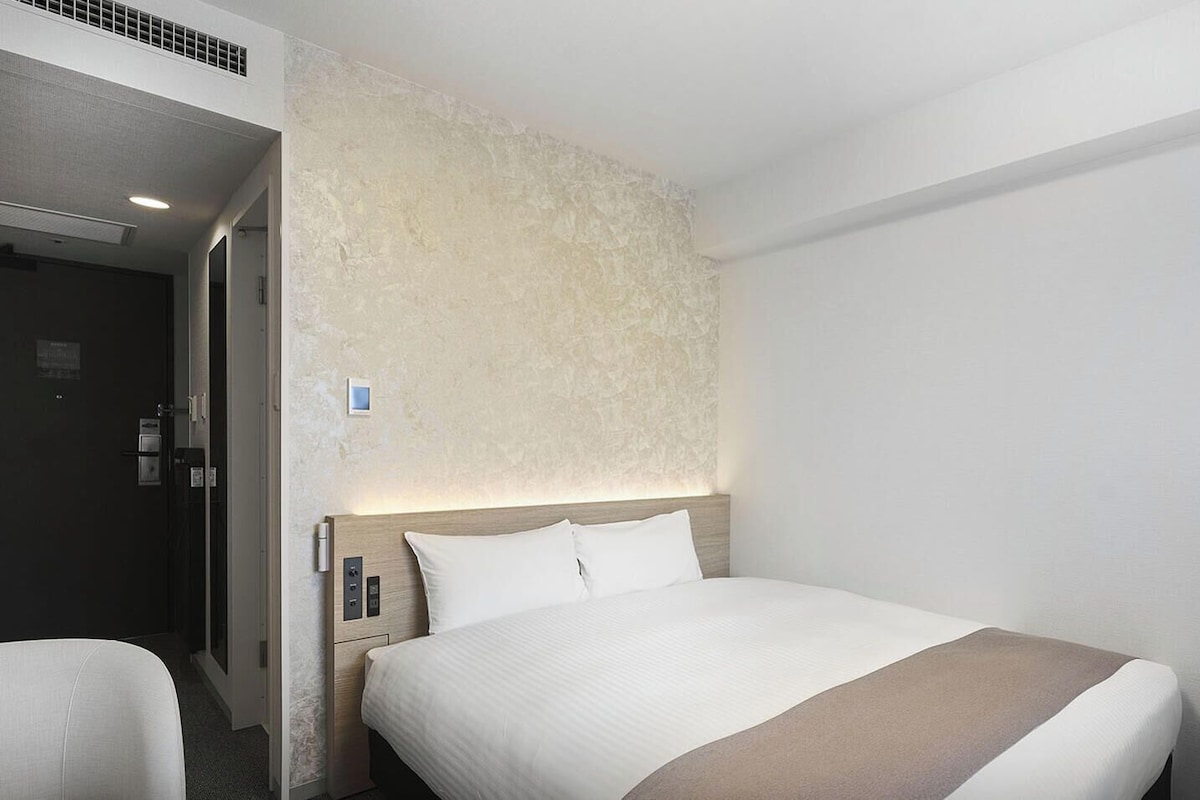Una habitación de hotel con una cama, un escritorio y una puerta.