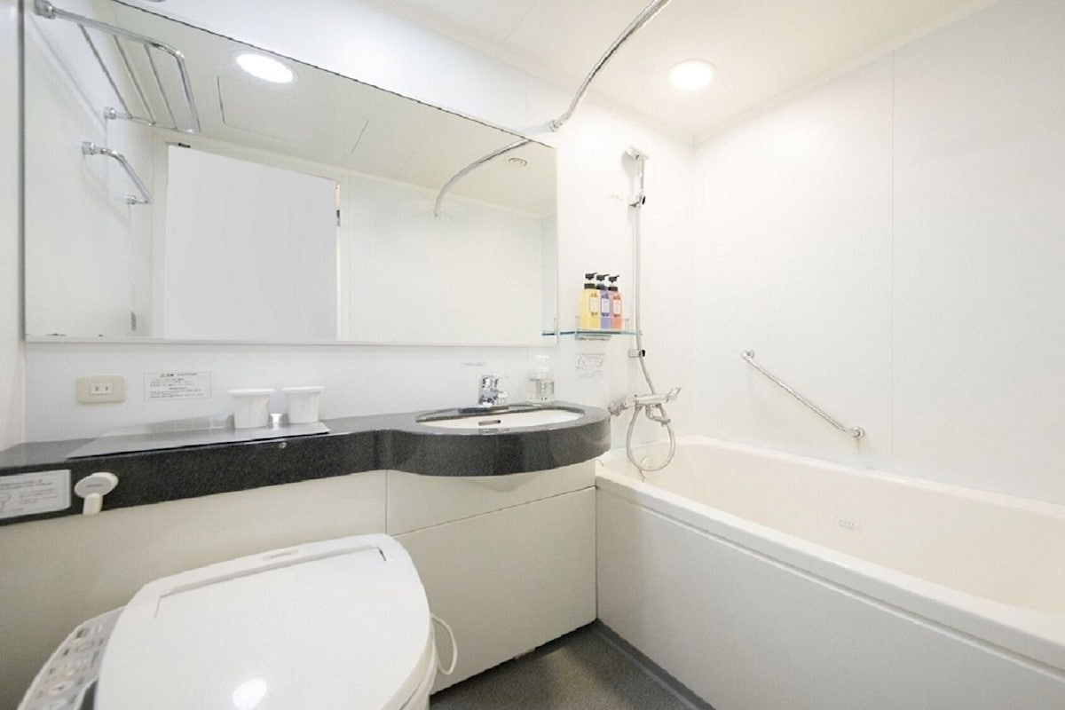 Un baño con lavamanos, espejo y bañera blancos.