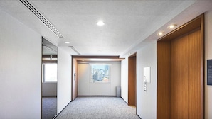 Un pasillo con piso alfombrado, una puerta de madera y una ventana con vista a la ciudad.