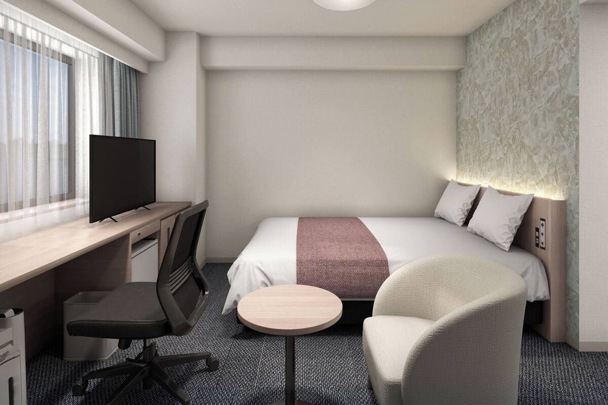 Une chambre d’hôtel avec un lit, un bureau, une chaise, une télévision et une petite table.