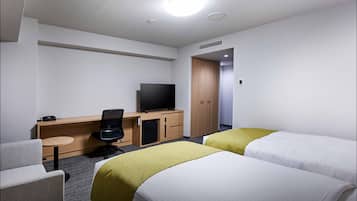 A hotel room with two beds, a desk with a television, a chair, and a small table.