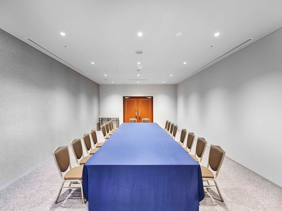 A conference room with a long table, beige chairs, and a blue tablecloth.
