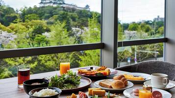 A breakfast table with various dishes, a cup of coffee, and a view of a castle.