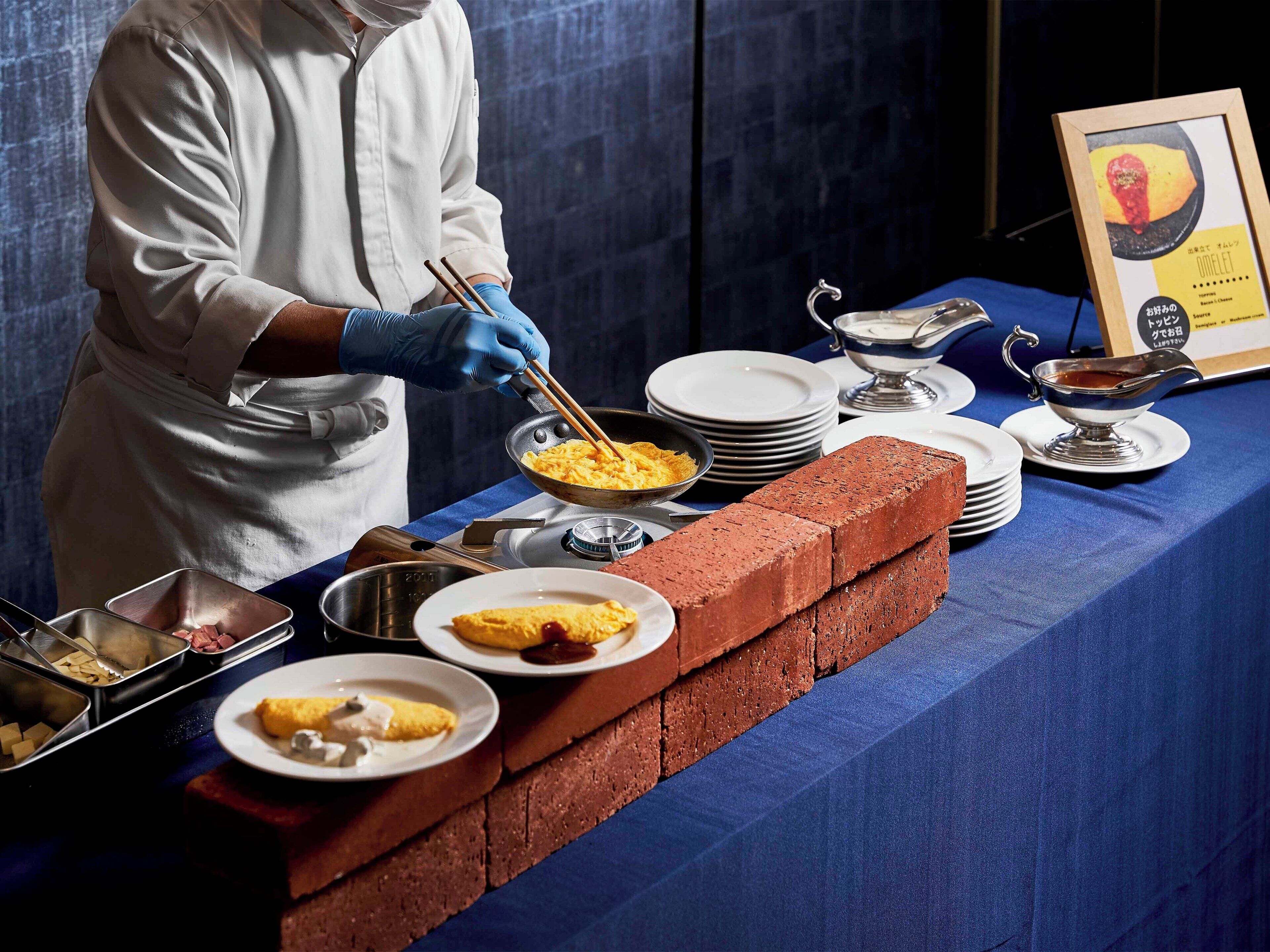 A buffet setup with a variety of dishes, including omelets and a brick barrier.
