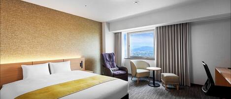 Habitación de hotel con una cama grande, una silla de masaje, un escritorio y vistas de la ciudad desde la ventana.