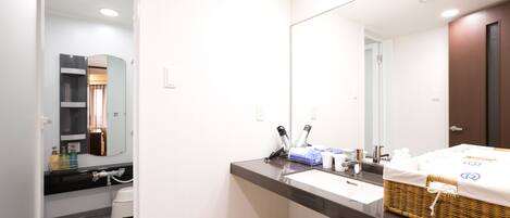 A modern bathroom with a large mirror, two sinks, and a wicker basket on the counter.
