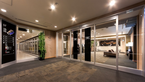 Un vestíbulo de hotel con mostrador de recepción, una zona de estar y una escalera que conduce a los pisos superiores.