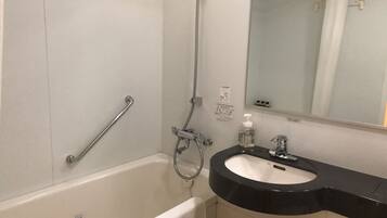 Un baño con bañera, lavabo, espejo y barra de apoyo.