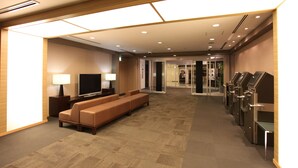 Un hall de hotel con un sofá, televisor y máquinas de autoservicio.