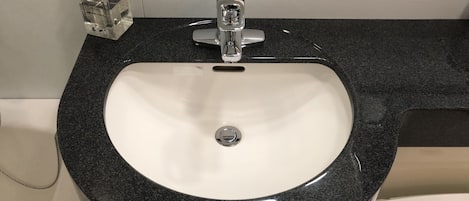 A bathroom sink with a black granite countertop, a faucet, and a soap dispenser.