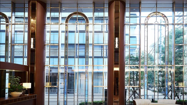 A modern lobby with large windows, a seating area, and a reception desk.