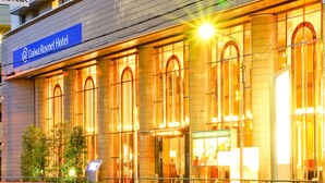 The exterior of Daiwa Roynet Hotel with large arched windows and a prominent sign.