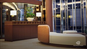 A modern lobby with a curved reception desk, a potted plant, and a seating area.
