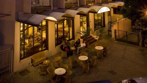 Un hotel con varios balcones, mobiliario exterior y una entrada bien iluminada.