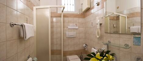 A bathroom with a shower, toilet, sink, and a mirror.