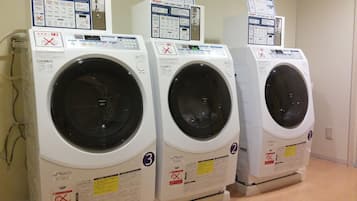 Three front-loading washing machines in a row, each with a control panel and safety instructions.
