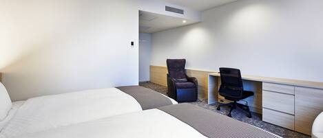 A hotel room with a large bed, a desk with a chair, and a small seating area.