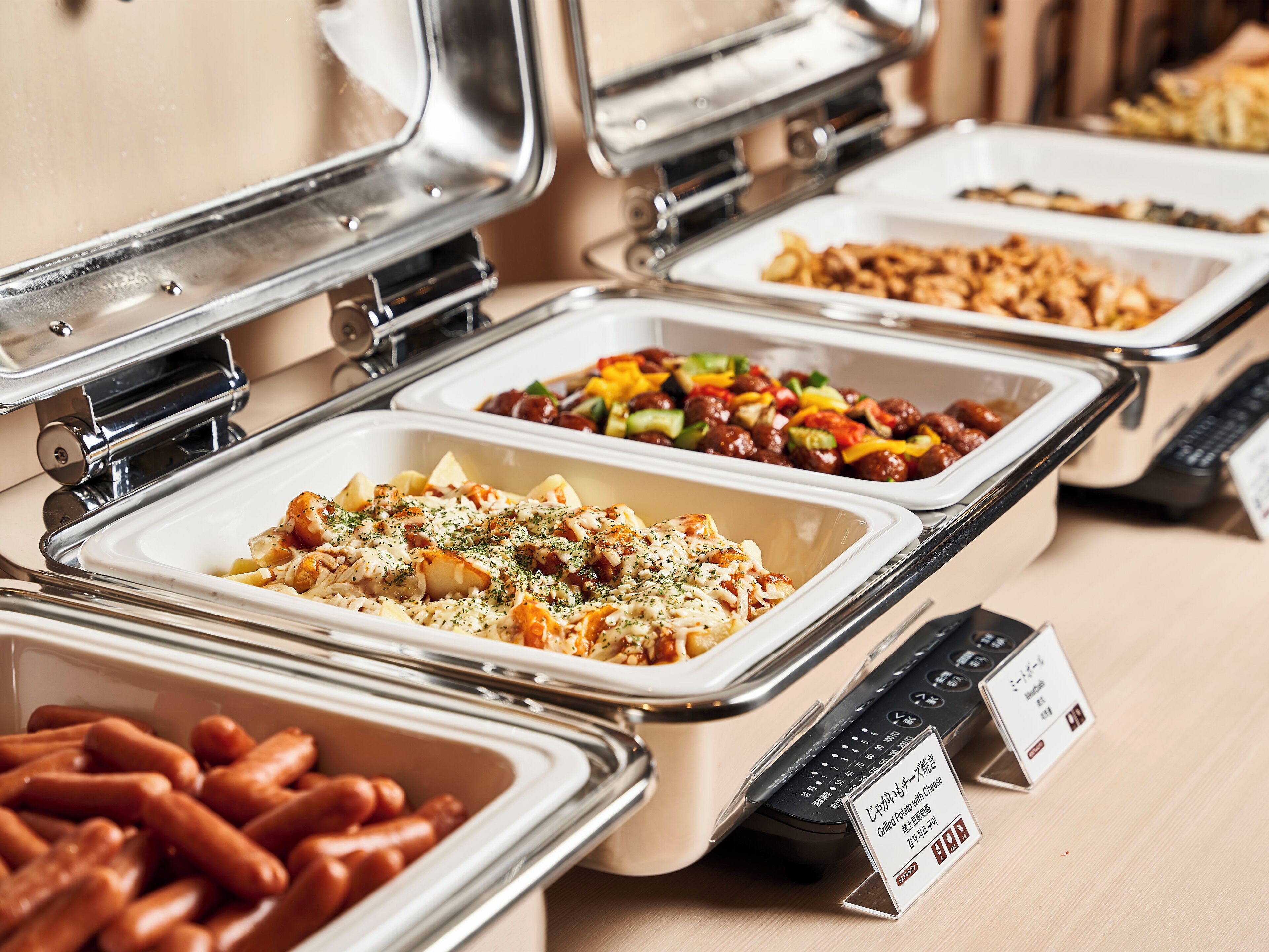 A buffet with various dishes including grilled potato with cheese, meatballs, and a vegetable salad.