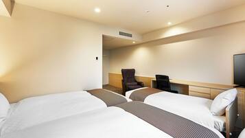 Ein Hotelzimmer mit zwei Betten, einem Schreibtisch, einem Stuhl und einem Fernseher.