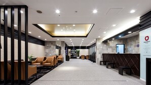 A modern hotel lobby with a reception desk, seating area, and a large illuminated ceiling feature. - Daiwa Roynet Hotel Kobe Sannomiya (Kobe)