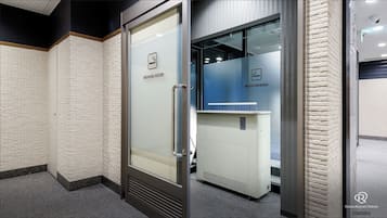 A hotel corridor with a glass door leading to a smoking room, a blue wall with a smoking room sign, and a white wall with a similar sign.
