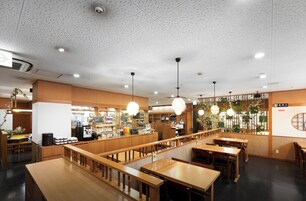 Un interior de restaurante con mobiliario de madera, iluminación colgante y una zona de barra.