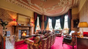 A room with a patterned sofa, a fireplace, and a red carpet. - Kildonan Lodge Hotel (Edinburgh)