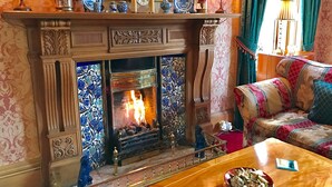 A cozy room with a fireplace, a sofa, and a table with a bowl. - Kildonan Lodge Hotel (Edinburgh)