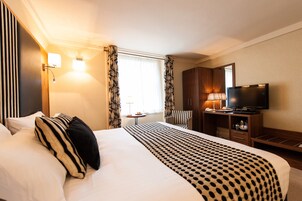 Een hotelkamer met een groot bed, een televisie, een bureau en een stoel.
