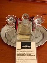 A tray with three clear glass bottles of liquor and a thank you note from the Kildonan Lodge Hotel.