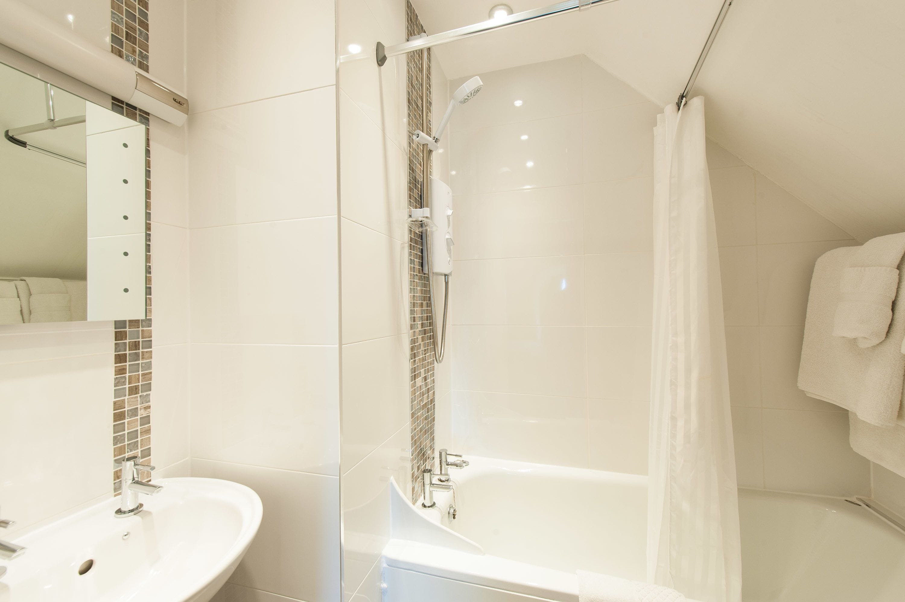 A modern bathroom with a glass-enclosed shower, a white bathtub, and a vanity with a mirror.