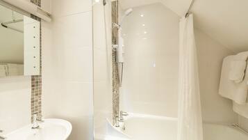 A modern bathroom with a glass-enclosed shower, a white bathtub, and a vanity with a mirror.