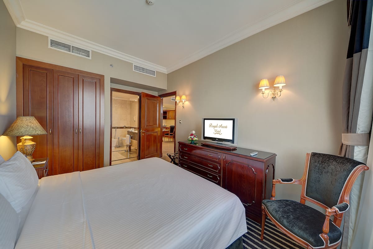 Une chambre d’hôtel avec un grand lit, une armoire en bois, une télévision et une chaise.