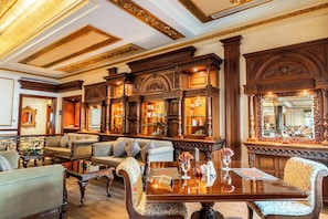 A luxurious room with ornate woodwork, a large mirror, and a seating area with sofas and a coffee table.