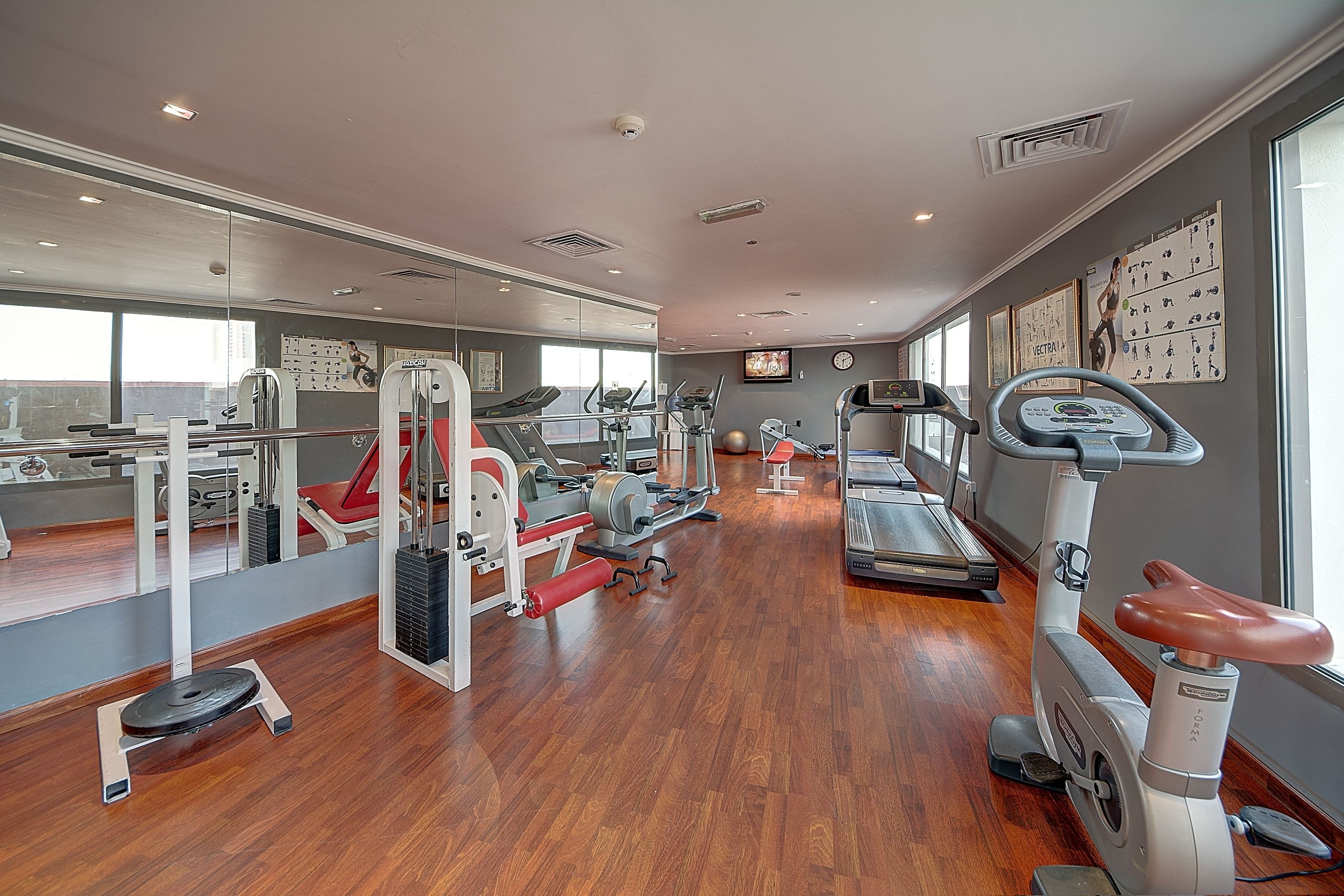 A gym with cardio machines, weightlifting equipment, and mirrors on the walls.